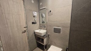 Ein Badezimmer mit Holztür, Waschbecken mit Spiegel, Duschbrause und Toilette.