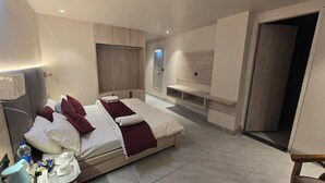 Ein modernes Hotelzimmer mit einem großen Bett, integriertem Fernseher und einer kleinen Sitzecke.