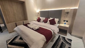 Ein modernes Hotelzimmer mit einem großen Bett, Nachttischen, einem Kleiderschrank und einer Deckenleuchte.