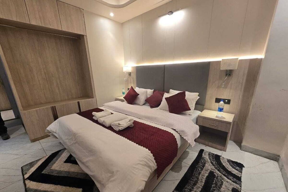 Une chambre d’hôtel moderne, dotée d’un grand lit, de tables de chevet, d’une armoire et d’un luminaire au plafond.