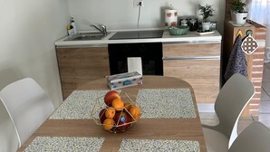 Moderni keittiö, jossa on puiset kaapit, pesuallas ja ruokailutila, jossa on pöytä neljälle henkilölle.