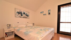 Een slaapkamer met een bed, nachtkastje en wanddecoratie.