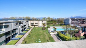 Un hotel moderno con piscina, césped cuidado y vistas a montañas lejanas.