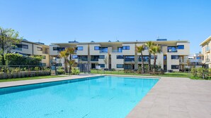 Un moderno edificio de apartamentos con piscina, balcones y palmeras.