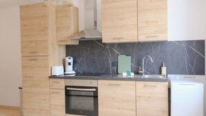 Une cuisine moderne avec des meubles en bois, un four encastré, une machine à café, un évier et un lave-vaisselle.