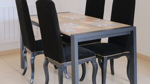 Une table à manger avec quatre chaises, un luminaire suspendu et un radiateur.