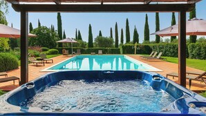 A hot tub with a wooden pergola overhead, a swimming pool, and lounge chairs. - Ghiaccio Bosco Capalbio (Capalbio)
