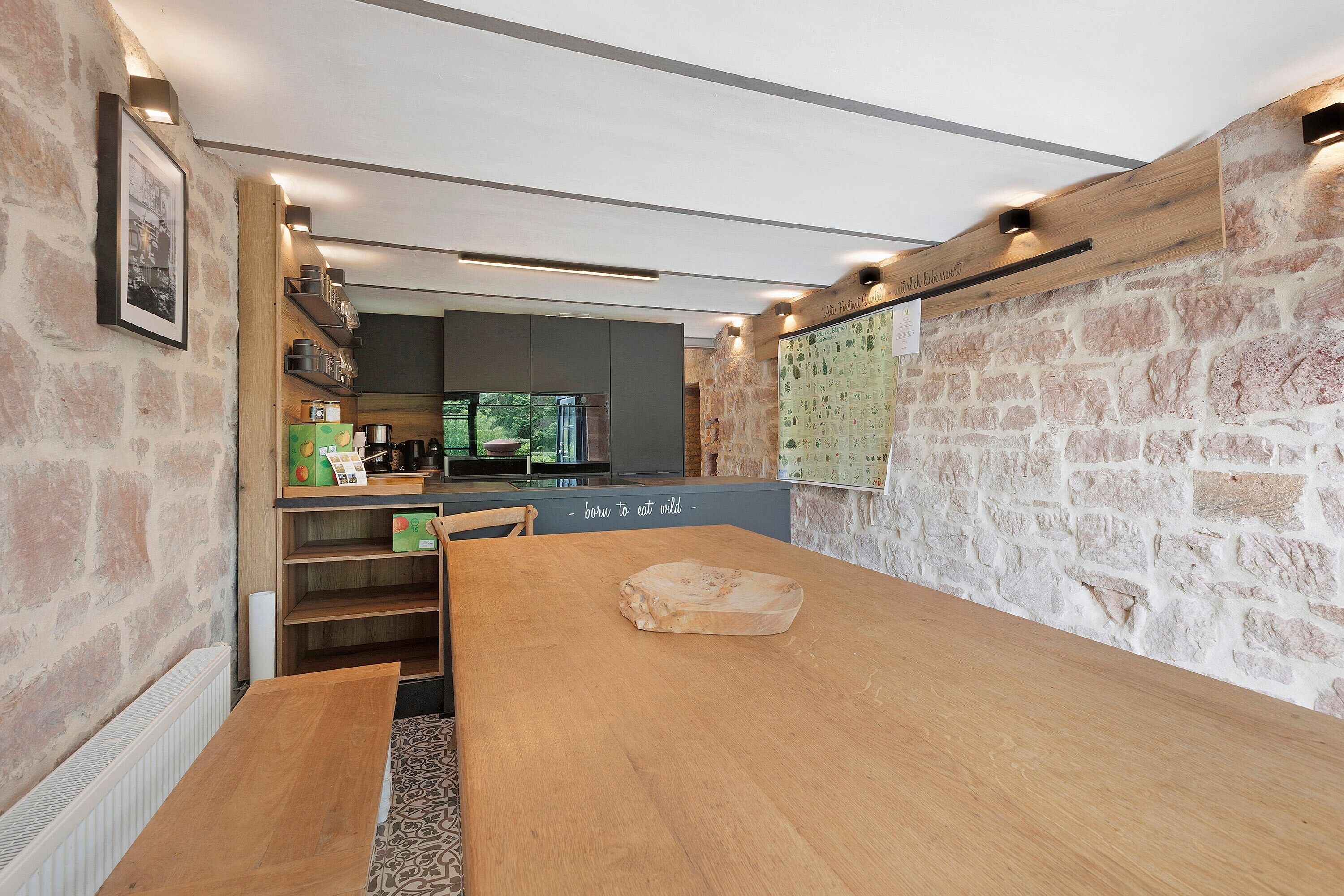 Een moderne keuken met een houten tafel, stenen muren en uitzicht op de omgeving.
