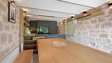 A modern kitchen with a wooden table, stone walls, and a view of the outdoors.