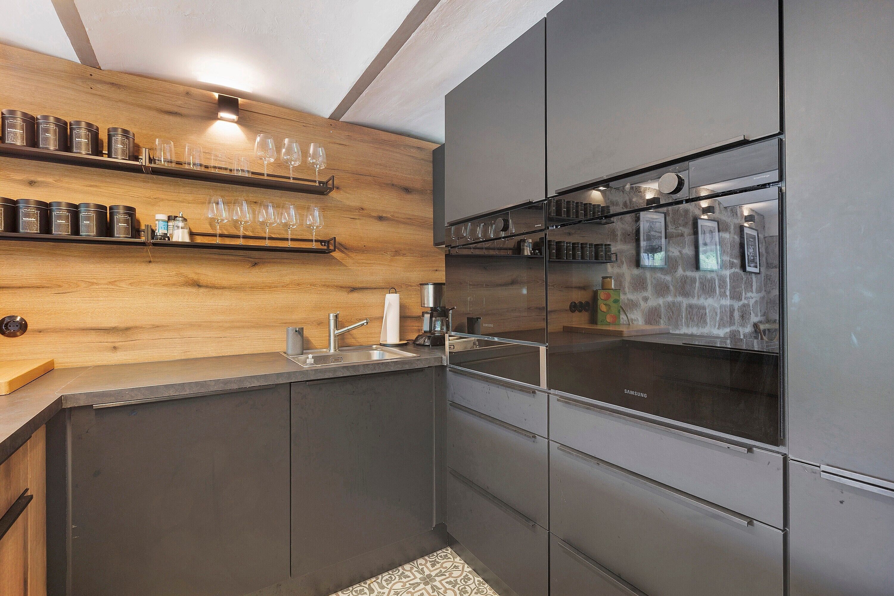Une cuisine moderne dotée d’appareils électroménagers en acier inoxydable, d’étagères en bois et d’un meuble à vin intégré.