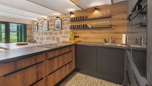 Une cuisine moderne avec un mur d’accent en pierre, des meubles en bois et des étagères à vin intégrées.