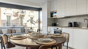 Een moderne eetruimte met een ronde tafel gedekt voor vier personen, omringd door rieten stoelen.