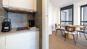 Et moderne køkken med indbygget komfur, kaffemaskine og spiseplads med et rundt bord og stole.