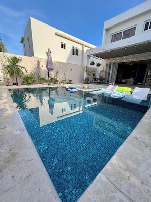 Une piscine à l’eau d’un bleu cristallin, entourée d’une terrasse aménagée avec des chaises longues et des parasols.