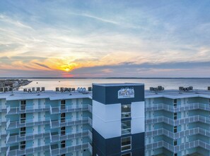 Un hôtel à plusieurs étages offrant une vue sur l’océan au coucher du soleil, avec une enseigne indiquant « Bay Club Ocean City ».
