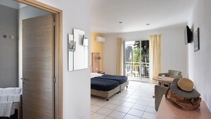 A hotel room with a bed, a desk, a chair, a balcony with curtains, and a view of the outside. - La Residence Maristella (Aregno)