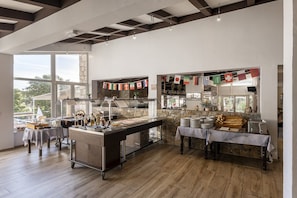 A buffet setup with a variety of food items and a stone wall backdrop. - Hôtel Maristella (Aregno)