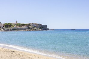 A coastal town with buildings near the water, a clear sky, and a calm sea.