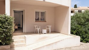 A building with a covered outdoor seating area, a staircase leading to the entrance, and a door. - La Residence Maristella (Aregno)