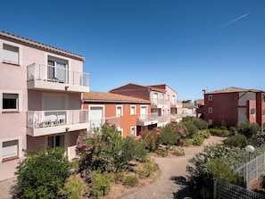 A residential building with balconies, a paved pathway, and surrounding greenery. - La Residence Maristella (Algajola)