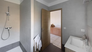 A modern bathroom with a shower, a bathtub, and a wooden door leading to a balcony. - La Residence Maristella (Aregno)