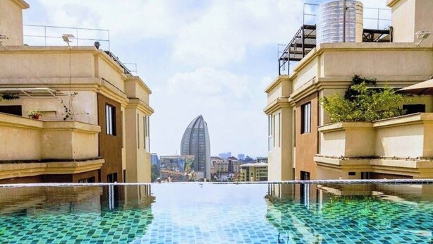 Une piscine dont le fond est recouvert de carreaux disposés en motif à damier, entourée d’immeubles dotés de balcons.