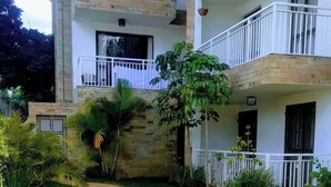 Un immeuble à plusieurs étages doté de balcons, d’un mur en pierre et d’une pelouse bien entretenue, avec un chemin sinueux.