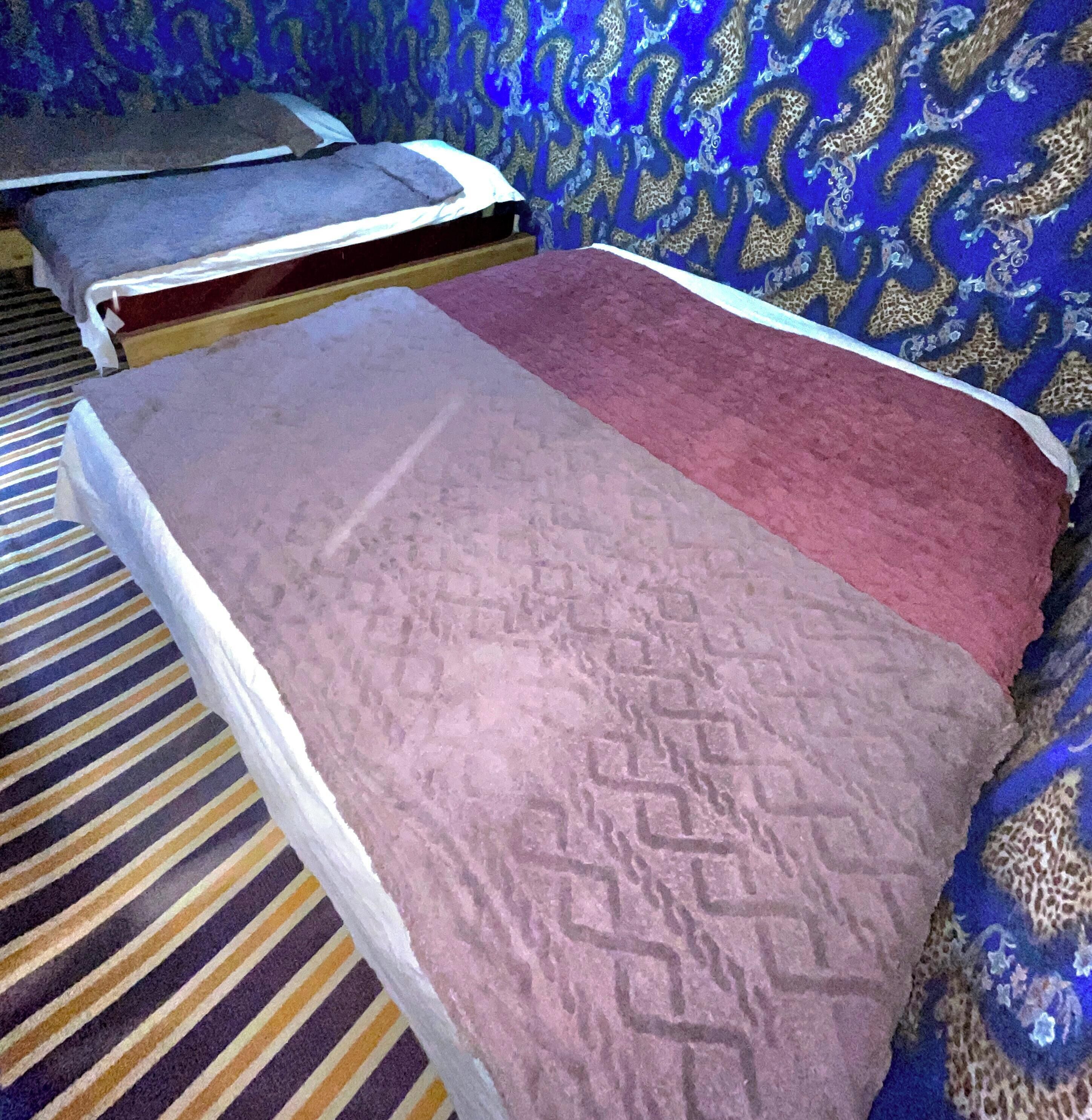 Una habitación con una cama, una alfombra a rayas y un papel tapiz estampado.