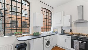 A modern kitchen with white cabinetry, a washing machine, and a stove. - 2 Bedroom Birmingham J Quarter With Parking & Wifi (Birmingham)