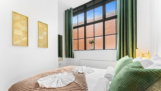 A neatly arranged bedroom with a large window, a radiator, and two framed artworks on the wall. - 2 Bedroom Birmingham J Quarter With Parking & Wifi (Birmingham)