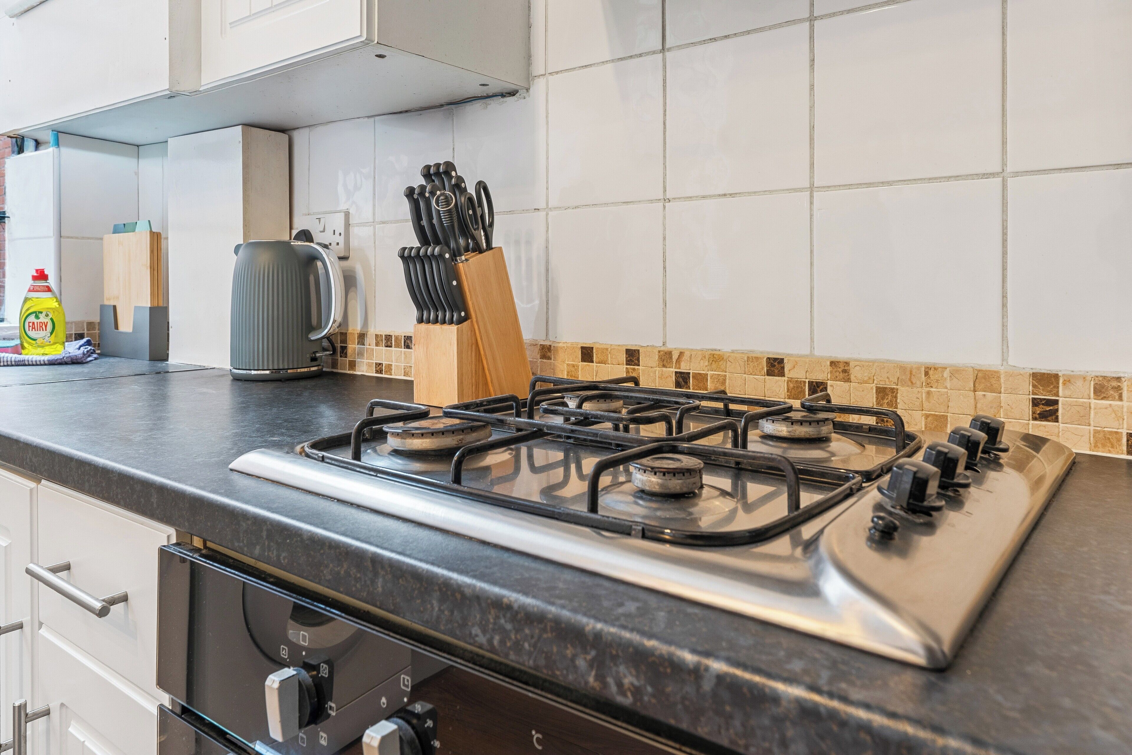 Une cuisine équipée d’une cuisinière à gaz, d’une bouilloire et d’un bloc à couteaux.