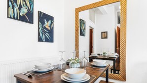 A dining area with a wooden table set for four, a large mirror, and two wall-mounted paintings. - 2 Bedroom Birmingham J Quarter With Parking & Wifi (Birmingham)