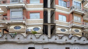 Ein mehrgeschossiges Gebäude mit Balkonen, Klimaanlagen und einem einzigartigen architektonischen Design mit Rundfenstern und dekorativen Elementen.