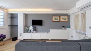 Ein modernes Wohnzimmer mit grauem Sofa, einem weißen Unterhaltungseinheit und einem Flachbildfernseher an der Wand.