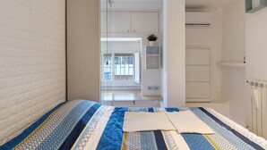 Ein Schlafzimmer mit Bett, weißem Kleiderschrank, Heizkörper und Fenster.