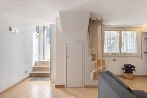 A modern interior with a staircase, a grey sofa, and a potted plant. - Smart Loft Apartment with Private Terrace, Wi-Fi, and Air Conditioning (Roma)