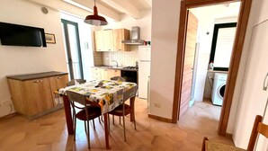 Eine kleine Küche mit Holzausstattung, einem Esstisch mit Stühlen und einer Waschmaschine im Hintergrund.