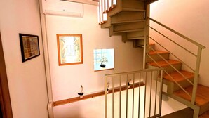 Eine Treppe mit Holzboden und Metallgeländer, eine Wand-Klimaanlage und gerahmte Kunstwerke.