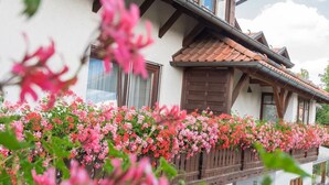 Ein Gebäude mit einem Balkon, der mit Blumen geschmückt ist, Holzläden und einem Ziegeldach.
