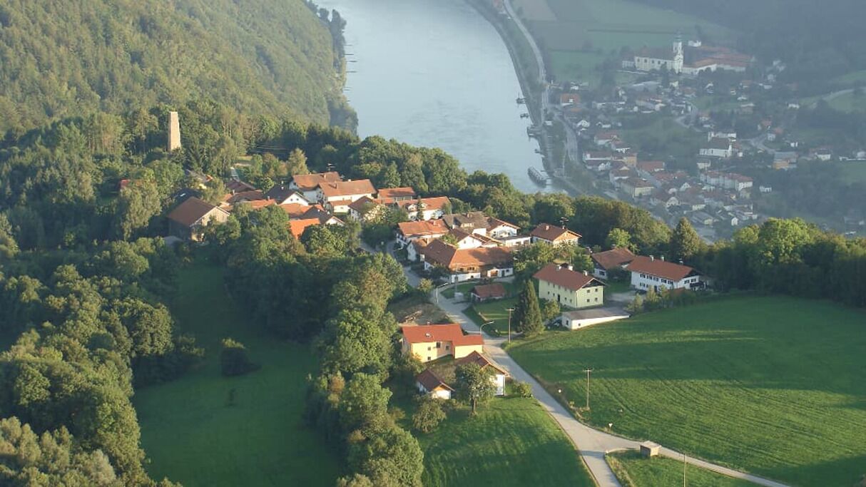 An aerial view of a village with houses, a church, and a river.