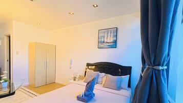 A hotel room with a bed, a wardrobe, a painting, and a view of the sea.