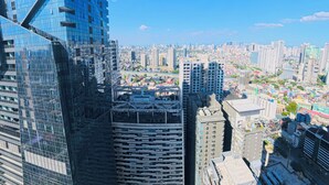 Un edificio alto con facciata in vetro moderno, circondato da altri grattacieli e un panorama urbano sullo sfondo.
