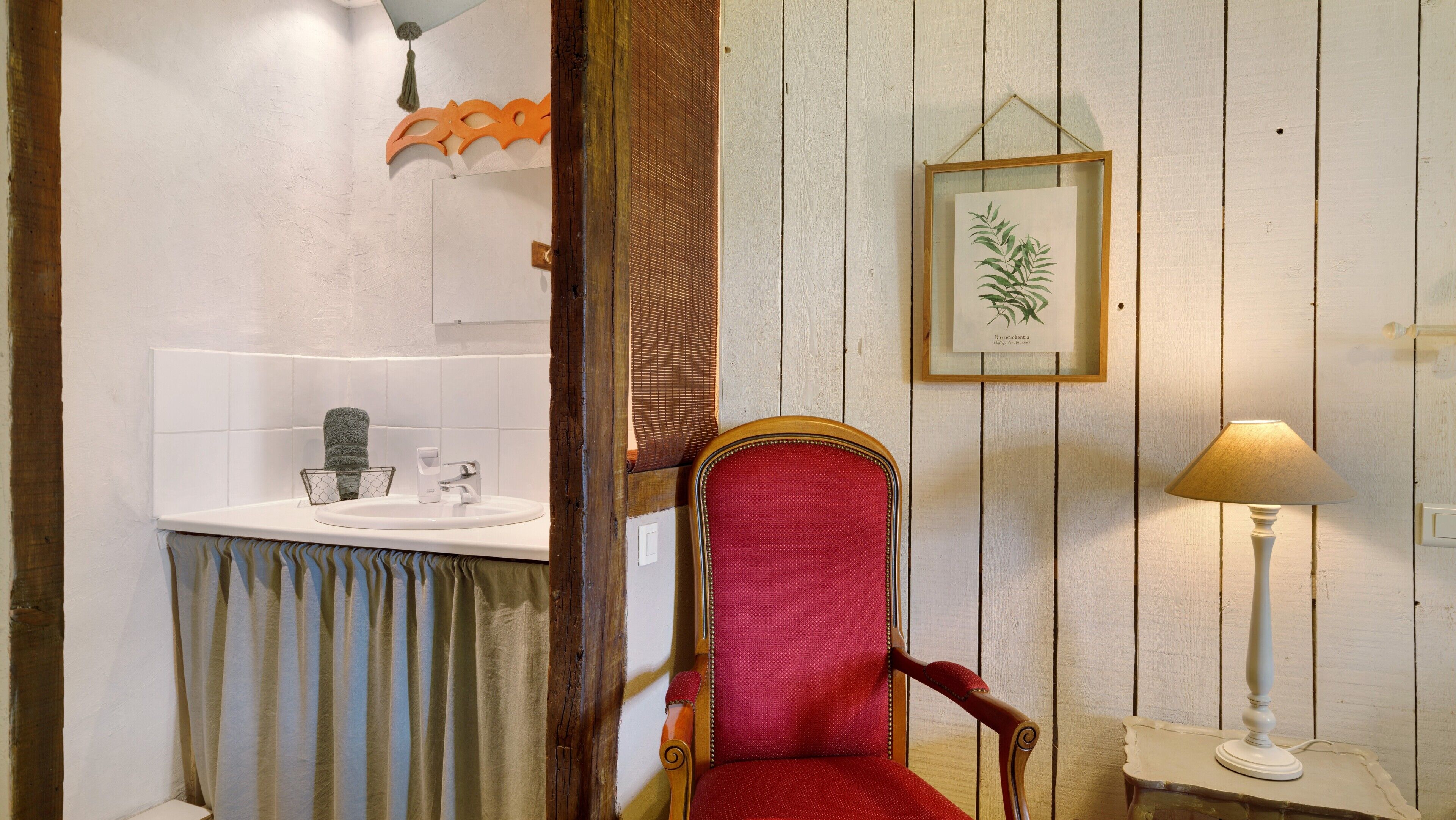 Une salle de bain avec un lavabo, un miroir et une illustration botanique encadrée accrochée au mur.