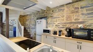 Una cocina con paredes de piedra, microondas, tostadora, cafetera y hervidor.