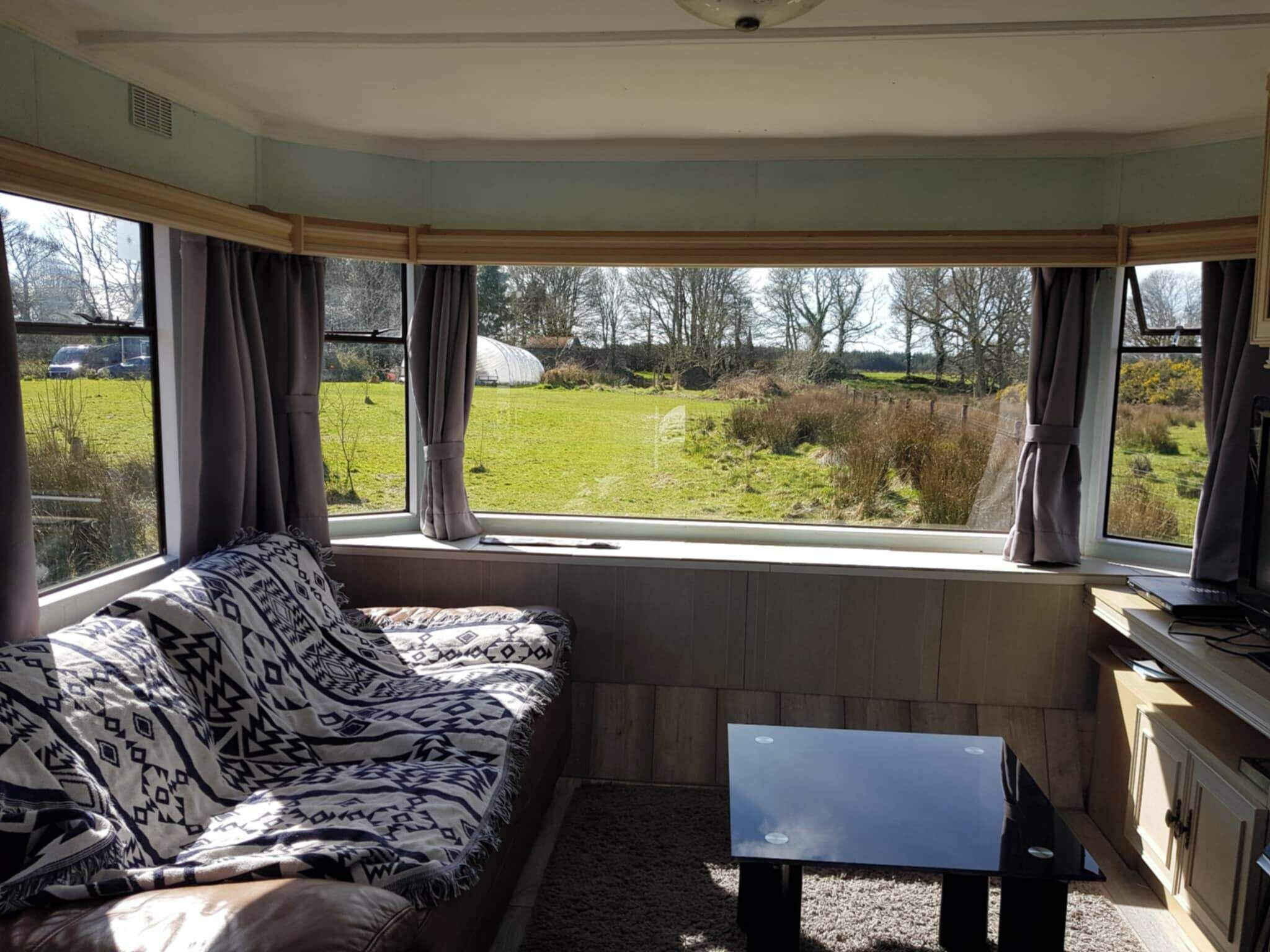 A room with a sofa facing a window, a small table, and a cabinet.