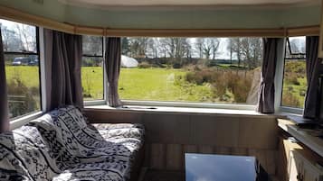 A room with a sofa facing a window, a small table, and a cabinet.