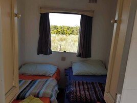 Una habitación pequeña con dos camas, una ventana con cortinas y vistas al exterior.