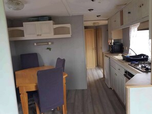 A compact kitchen with a dining table, chairs, cabinets, and a stove.