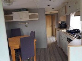 Una cocina compacta con mesa, sillas, armarios y estufa.