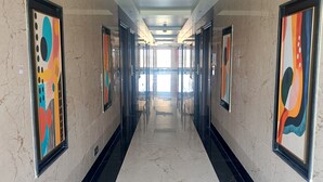 A hallway with marble walls, framed artwork, and a reflective floor. - Crystal Residency (Tiruchirappalli)